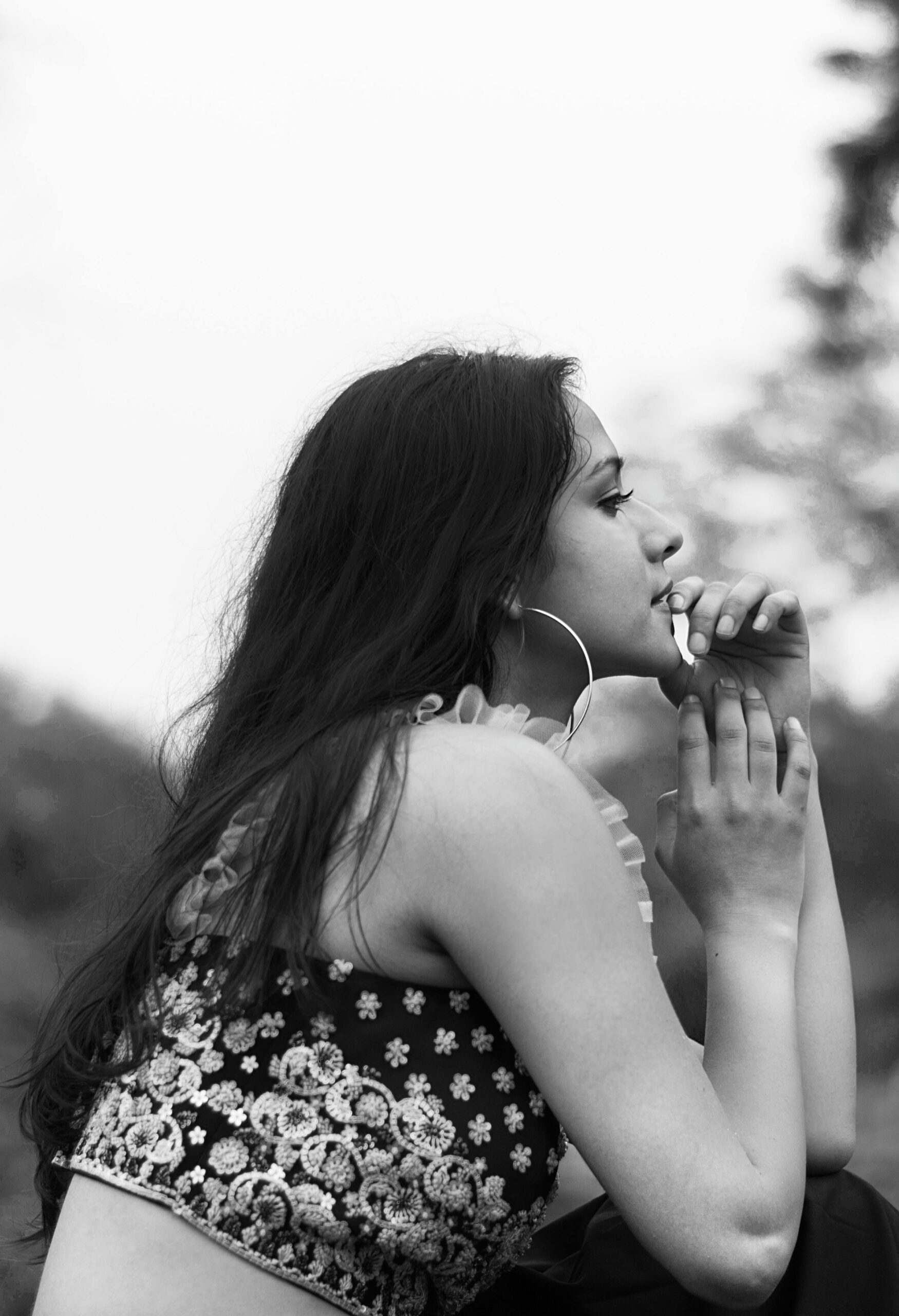 Black and white profile portrait of an adult woman sitting outdoors, exuding elegance and contemplation.
